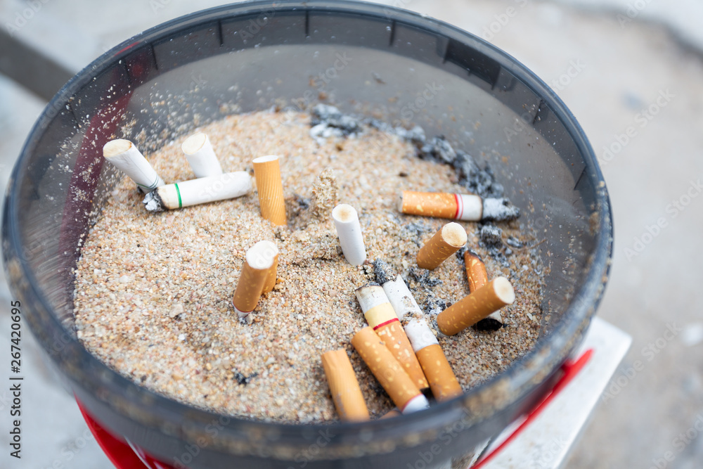 Top View Dirty black Ashtray full of cigarette butts Top View Dirty black Ashtray full of cigarette butts