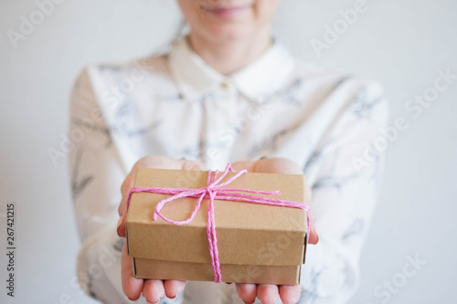 Female hands holding a small gift wrapped with pink ribbon. Selective focus,Selective focus, happy birthday
