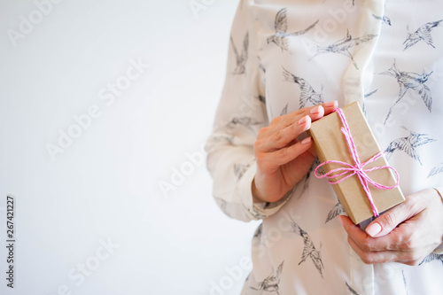 Female hands holding a small gift wrapped with pink ribbon. Selective focus,Selective focus, happy birthday
