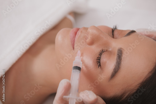 Attractive woman getting facial injections at cosmetology clinic. Attractive woman receiving hyaluronic acid injections by professional dermatologist. Rejuvenation concept