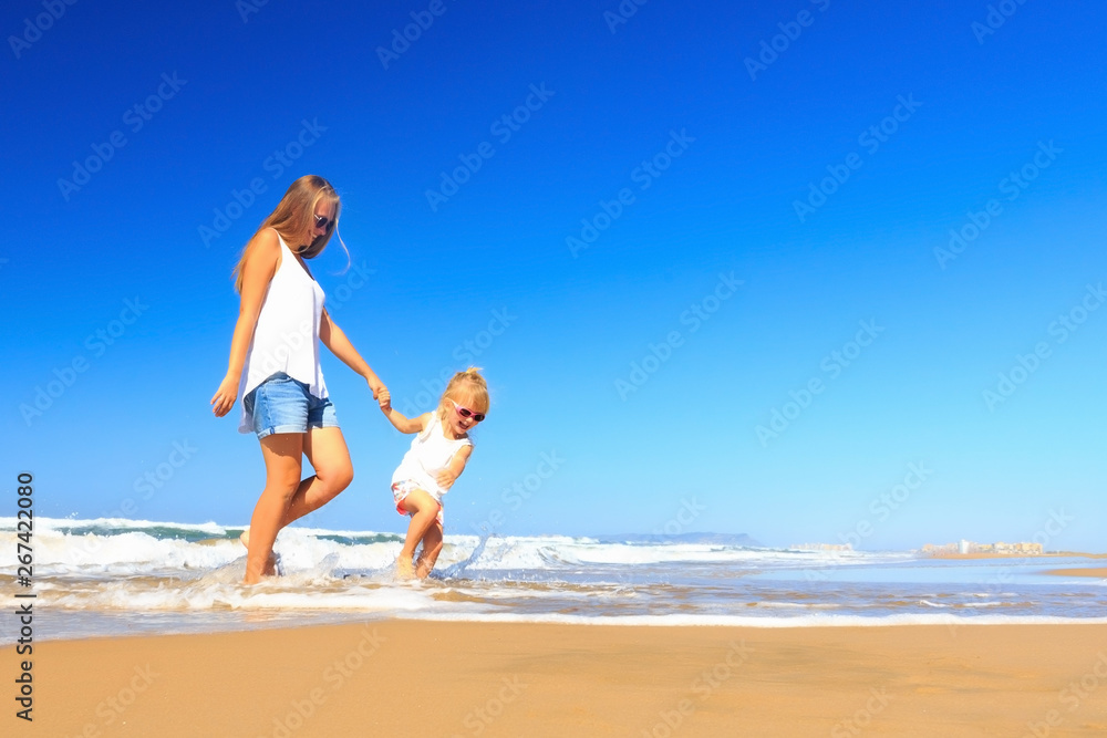 Happy mother and daughter spend their holidays on the seashore.