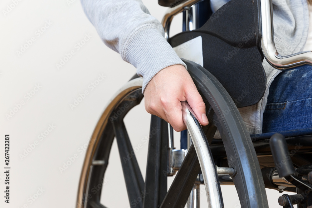Detail of disabled woman holding a hand on wheel of a wheelchair. Detail of disabled woman holding a hand on wheel of a wheelchair.