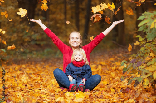Happy autumn. A mother and daughter are playing and laughing in an autumn park.