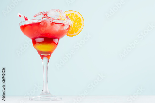 Wallpaper Mural Tropical alcohol sunrise drink - red, yellow liquor, oranges slice, straw, ice in misted glass on elegant green background. Torontodigital.ca
