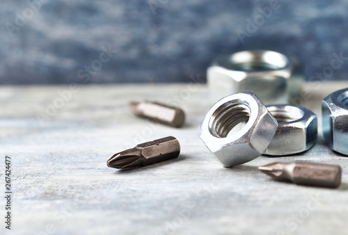 Hex nuts and bits for a screwdriveron wooden background. Close up. Copy space.  photo