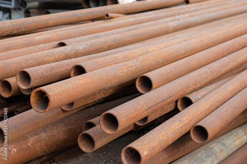 A pile of rusty metal pipes lies on the ground. Pipes for water and plumbing, closeup photo.