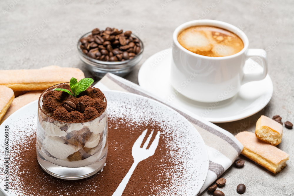 Classic tiramisu dessert in a glass and cup of coffee on concrete background Classic tiramisu dessert in a glass and cup of coffee on concrete background