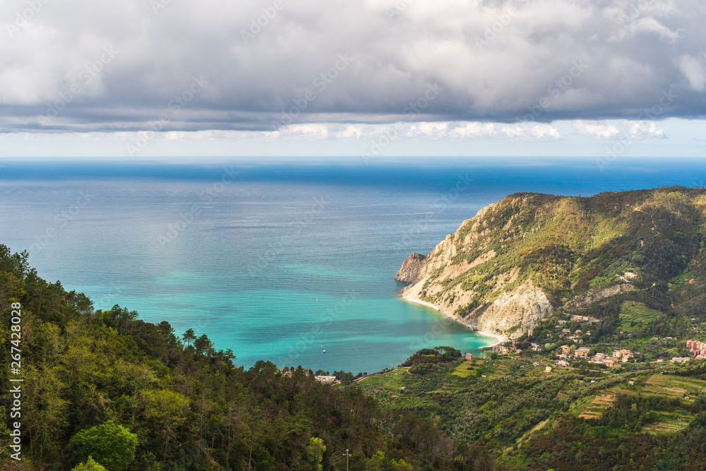 Coastal landscape with mountains and valleys on a spring day. View over the Ligurian Sea, from the red hiking path from Vernazza towards Monterosso in Cinque Terre, Italy.