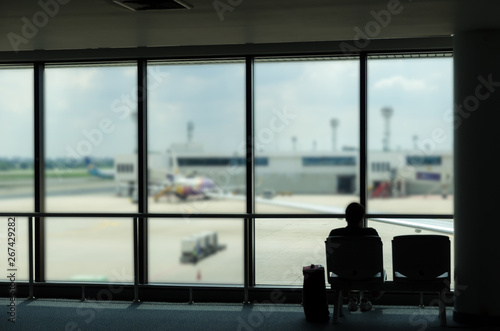 silhouette of business tourist people with luggage looking at airplanes and waiting at the plane boarding gates before departure in airport, travel, lifestyle and transportation concept
