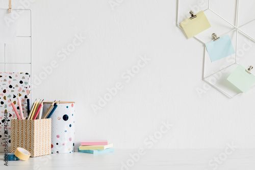 Desk with office supplies and post it notes on wall photo