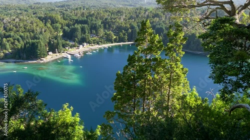 Looking between rich green pine trees at Villa La Angostura, Argentina. It is a town located on the northwest shore of the Nahuel Huapi Lake in Patagonia, Southern Andes. 4K