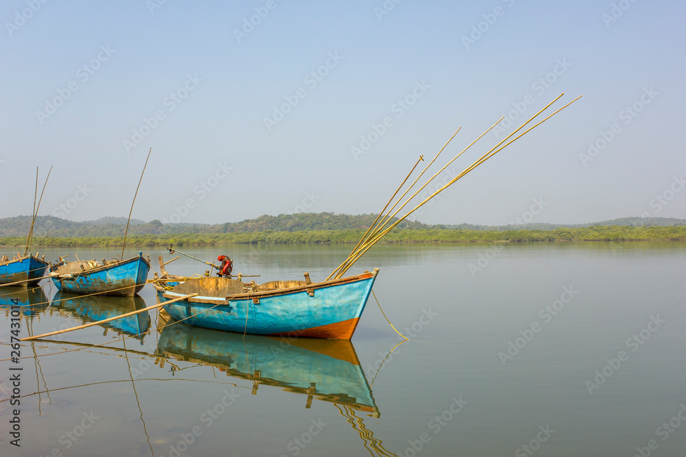 three empty boats with fishing rods and motors on the water against the backdrop of the river