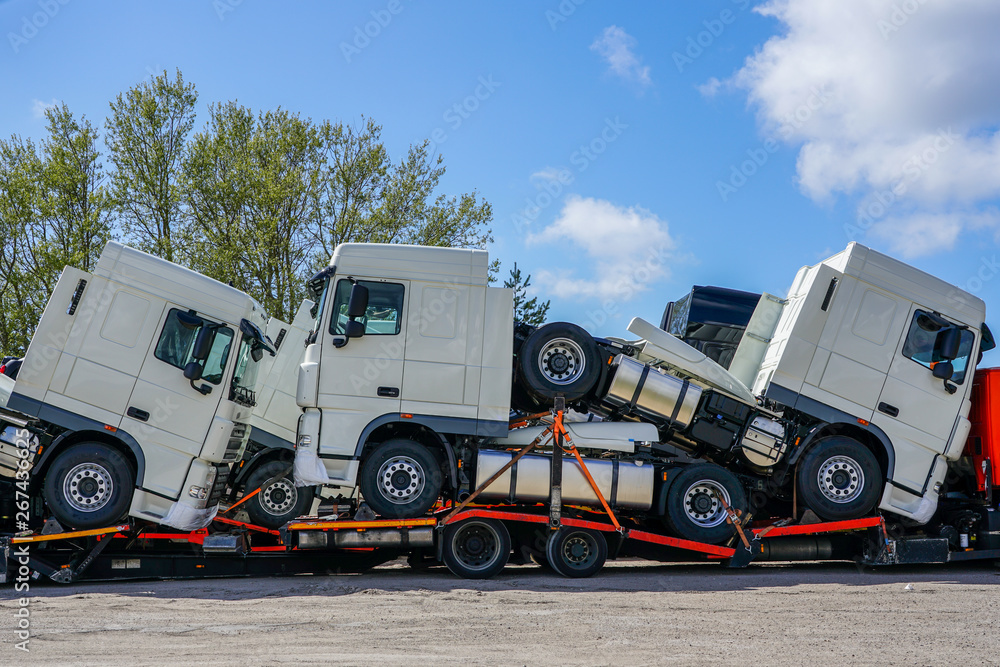 Obraz premium new trucks on a carrier truck, that delivers them to customers