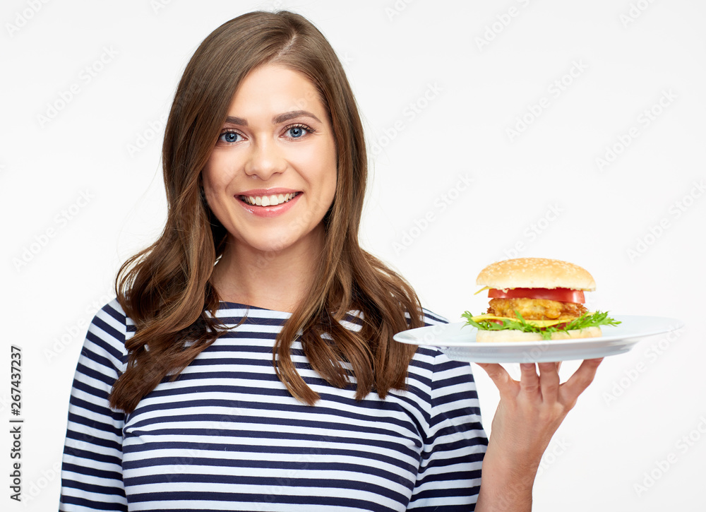 Smiling woman holding burger on white plate. Smiling woman holding burger on white plate.