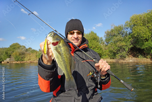 Lucky fisherman holding a larg bass fish. Freshwater fishing, lure fishing, boat fishing