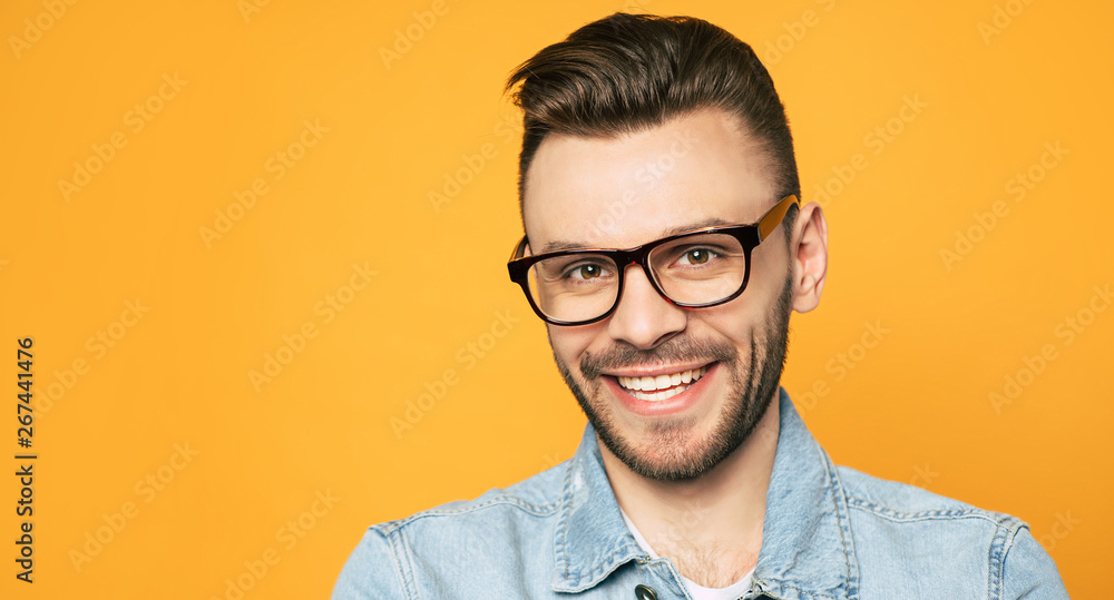 Close up portrait of handsome beard man in glasses isolated on yellow background