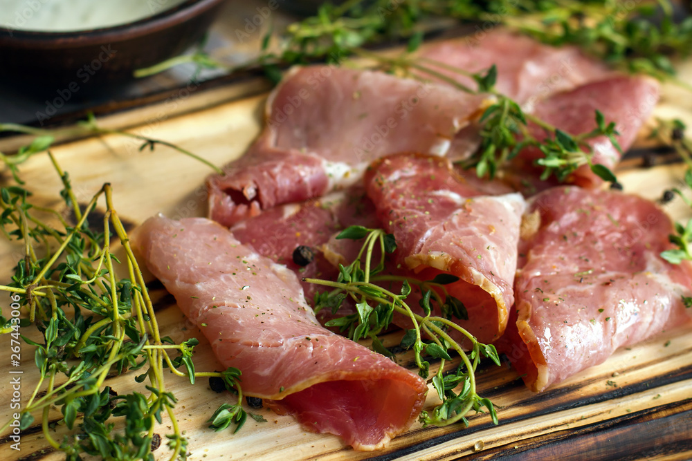 delicious pork bacon sliced into strips on a wooden background with spices and fresh thyme. A serving of low-fat succulent farm meat pork. Food Photography delicious pork bacon sliced into strips on a wooden background with spices and fresh thyme. A serving of low-fat succulent farm meat pork. Food Photography