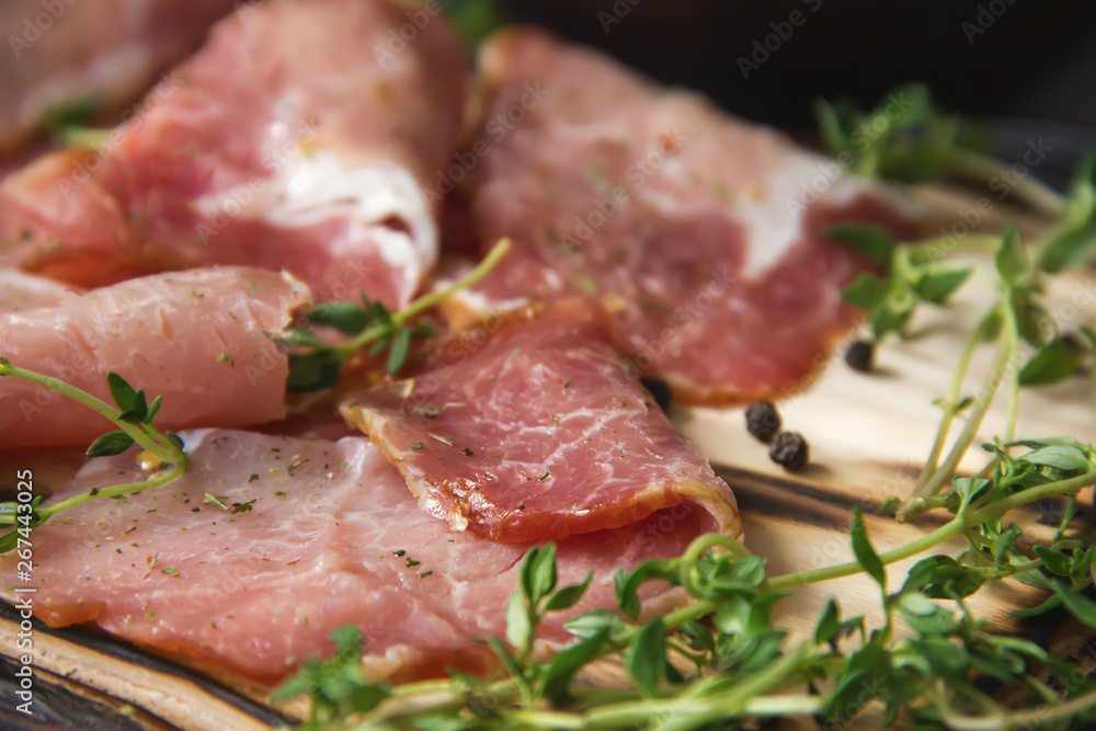 delicious pork bacon sliced ​​into strips on a wooden background with spices and fresh thyme. A serving of low-fat succulent farm meat pork. Food Photography