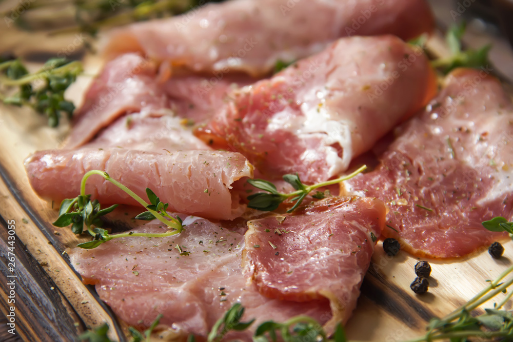 Delicious flavorful ham sliced ​​into strips on a wooden background with spices and fresh thyme. A serving of low-fat succulent farm meat pork. meat product. Food Photography