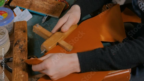 Professional male skinner, tanner working with genuine leather belt at workshop, studio. Handmade and leatherwork concept