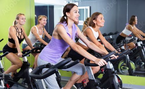 Girls during workout on stationary bicycle in fitness gym