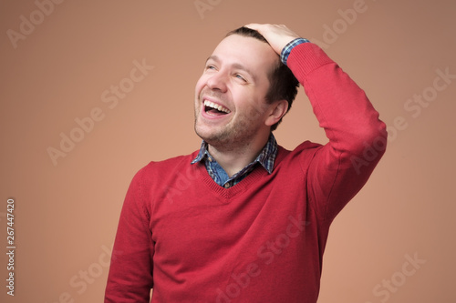 European young man in red sweater laughing on funny joke photo