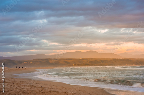 Rays of golden evening light falling on the Plettenberg Bay beach at sunset  with mountains in the distance. Garden Route  Western Cape  South Africa