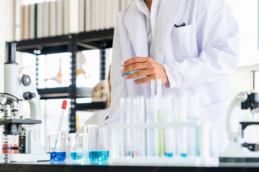 Scientists holding test tube while doing experimenting in the science room Scientists holding test tube while doing experimenting in the science room