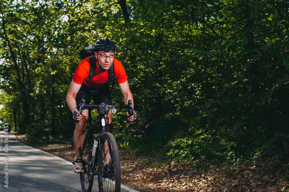 mountain biker rides through the forest road. summer. sport. fitness mountain biker rides through the forest road. summer. sport. fitness