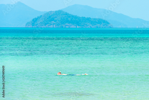 Male tourist snorkelling in the blue sea on a sunny day. © Tanes
