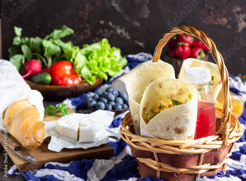 Fresh tortilla wraps with roasted chicken and vegetables, fresh juices, various vegetables and berries, fresh baguette and cheese. Ideas for picnic.