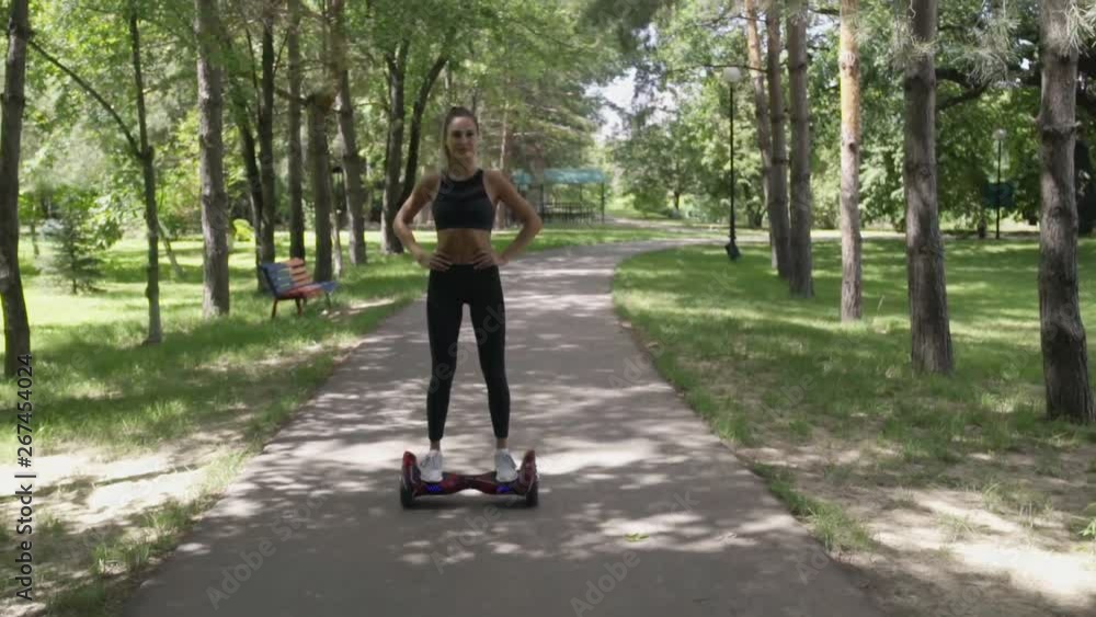 Beautiful girl with athletic body on hoverboard walking in park Beautiful girl with athletic body on hoverboard walking in park