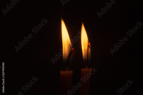 The flame of two burning candles on a dark background