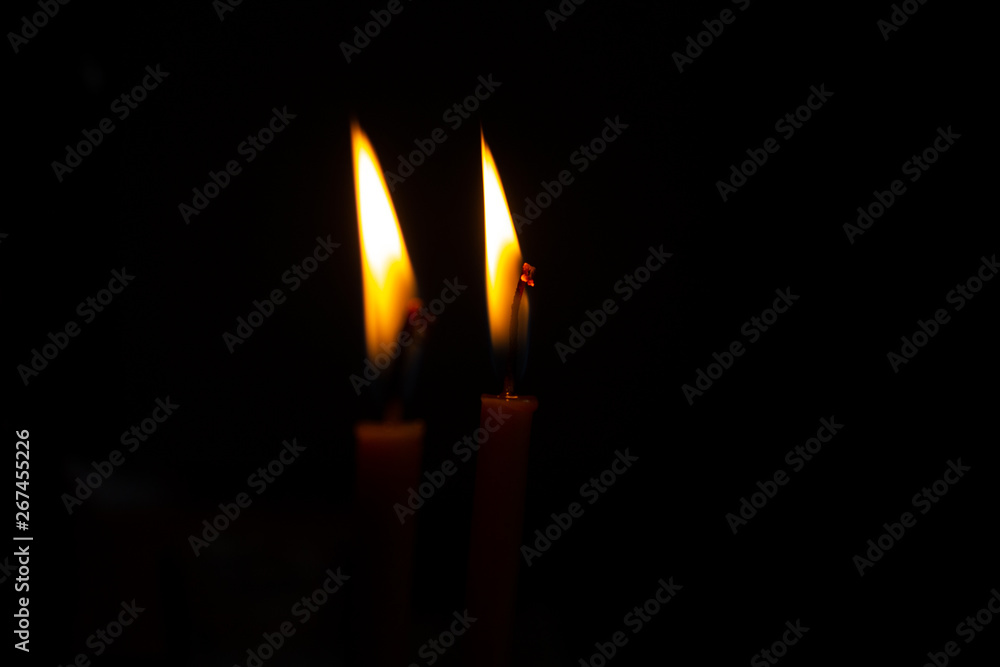 The flame of two burning candles on a dark background