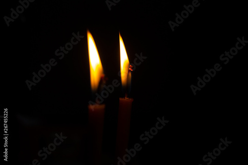 The flame of two burning candles on a dark background