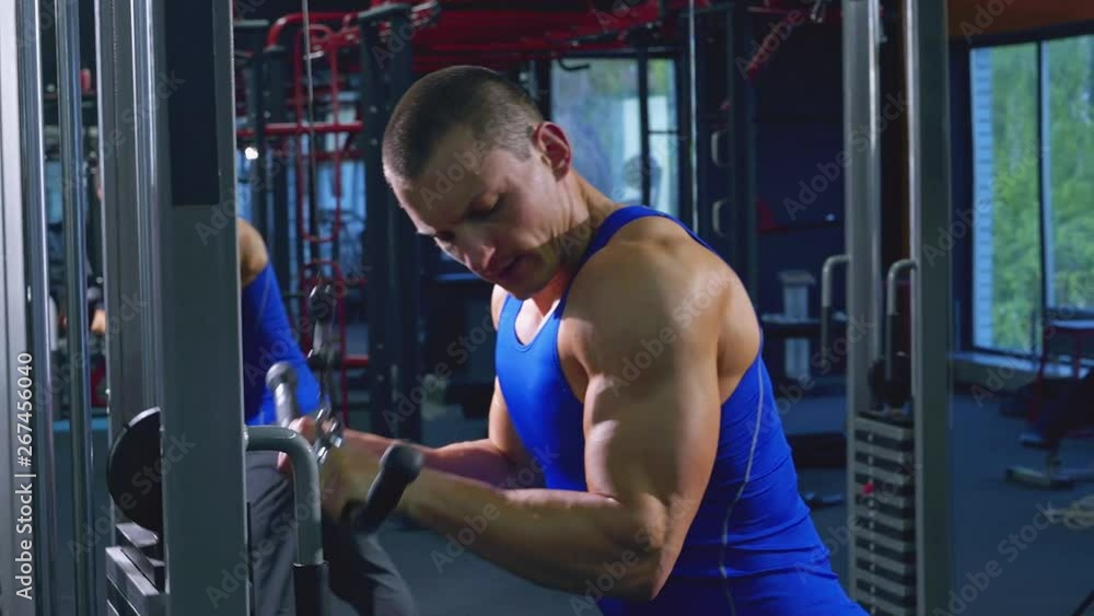 Muscular young man training in the gym, shaking the muscles of the hands with the help of an exercise machine. Preparing for the competition Muscular young man training in the gym, shaking the muscles of the hands with the help of an exercise machine. Preparing for the competition