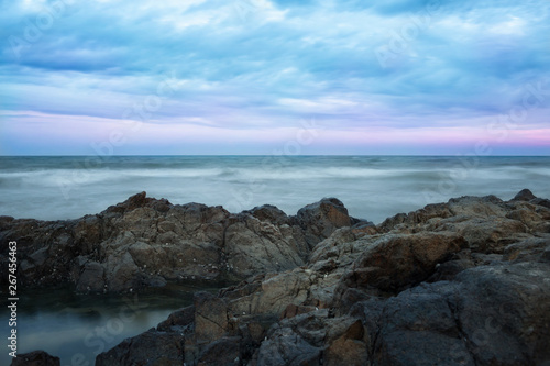 Stormy ocean and stony shore on the background of the sunset © oriolegin11