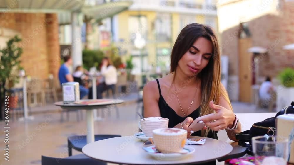 girl sitting in cafe and look in she phone and check a social sites girl sitting in cafe and look in she phone and check a social sites