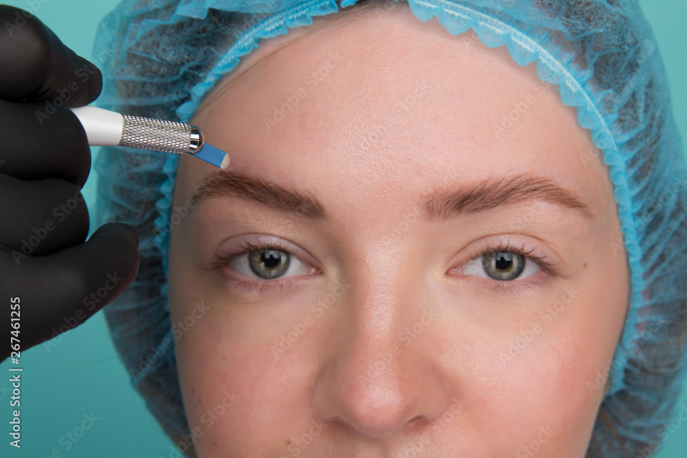 Permanent Makeup For Eyebrows. Microblading brow. Beautician Doing Eyebrow Tattooing For Female Face. Beautiful young girl in a beauty salon
