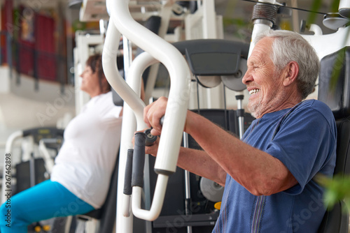 Senior man training on machine at fitness center. High-intensity workouts for senior people. Sport and workout concept.