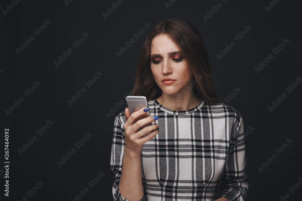 Sad teen being victim of cyber bullying online sitting on a couch in the living room at home Sad teen being victim of cyber bullying online sitting on a couch in the living room at home