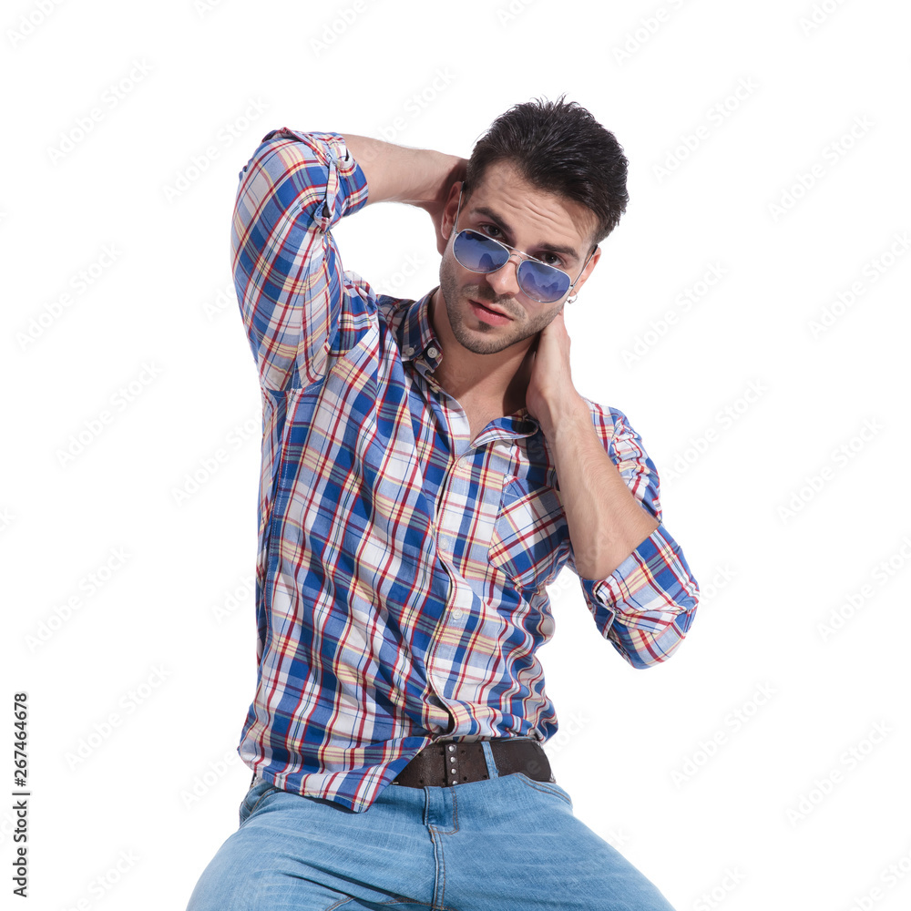 Charming guy sitting and holding his hand around his neck Charming guy sitting and holding his hand around his neck
