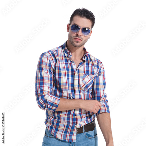 Confident man wearing sunglasse and adjusting his sleeve