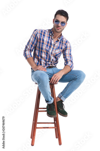 Attractive guy sitting on a stool and resting his arms