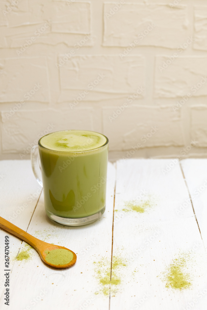 Matcha latte in a cup and a wooden spoon with matcha latte on white background, copy space Matcha latte in a cup and a wooden spoon with matcha latte on white background, copy space