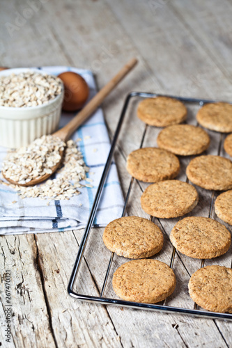 Baking grid with fresh oat cookies on rustic wooden table background  ingredients and kitchen utensil.