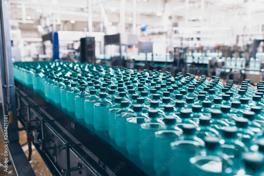 Fototapeta premium Bottling plant - Water bottling line for processing and bottling pure spring water into small bottles. Selective focus.