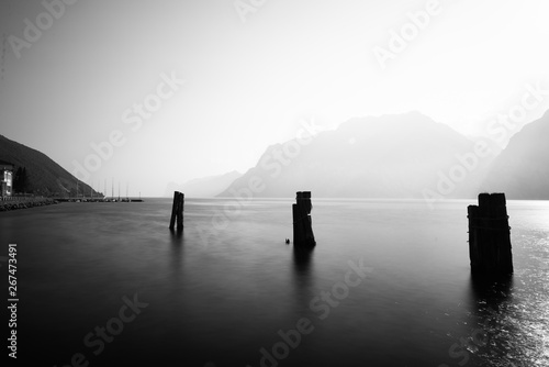 wood pole at a lake in the mountains in a bright sunlight in black and white