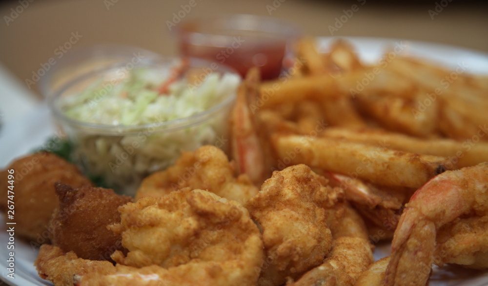 A fried shrimp dinner with french fries, cole slaw and hush puppies A fried shrimp dinner with french fries, cole slaw and hush puppies