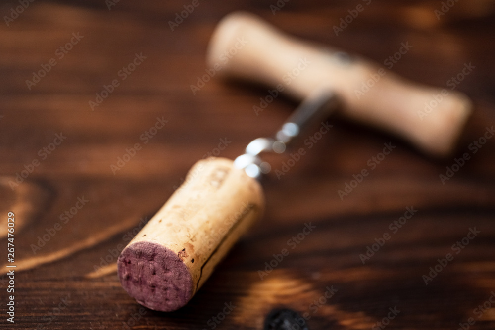 Corkscrew and a twisted cork on a wooden background.
